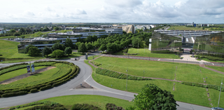 Vue aérienne de la technopole du Futuroscope, avec ses bâtiments modernes entourés d’espaces verts, de routes courbes et de ronds-points soigneusement aménagés.
